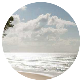 Image cropped into a circle of a beach, the sea and sky