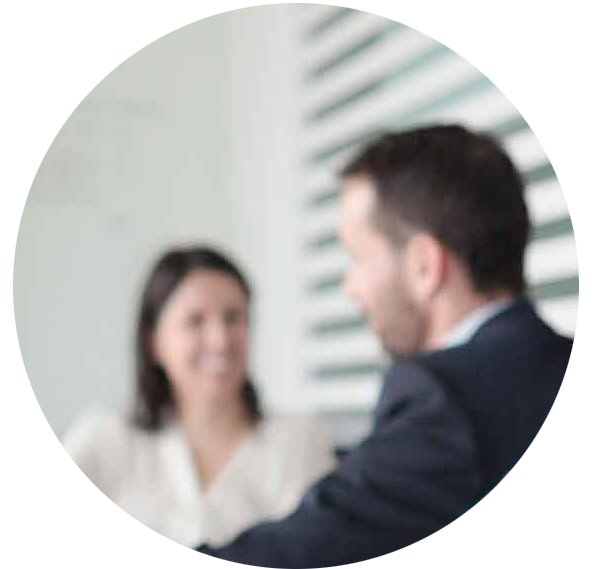 Blurred photo cropped into a circle of two people talking in a meeting room 