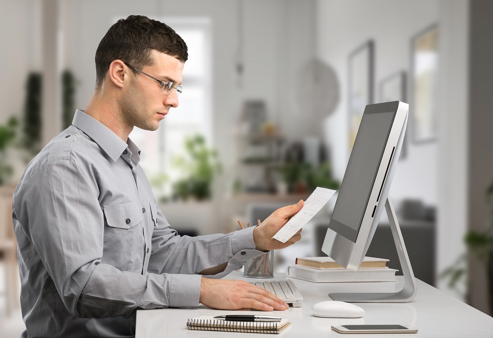 man sits at a desk in front of a computer