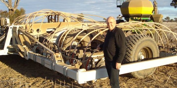 Cross Slot chief executive John Baker stands beside a no-tillage seed drilling machine in a field. Cross Slot's openers, or blades, will be distributed across the United States thanks to a new partnership with a Wisconsin-based company.